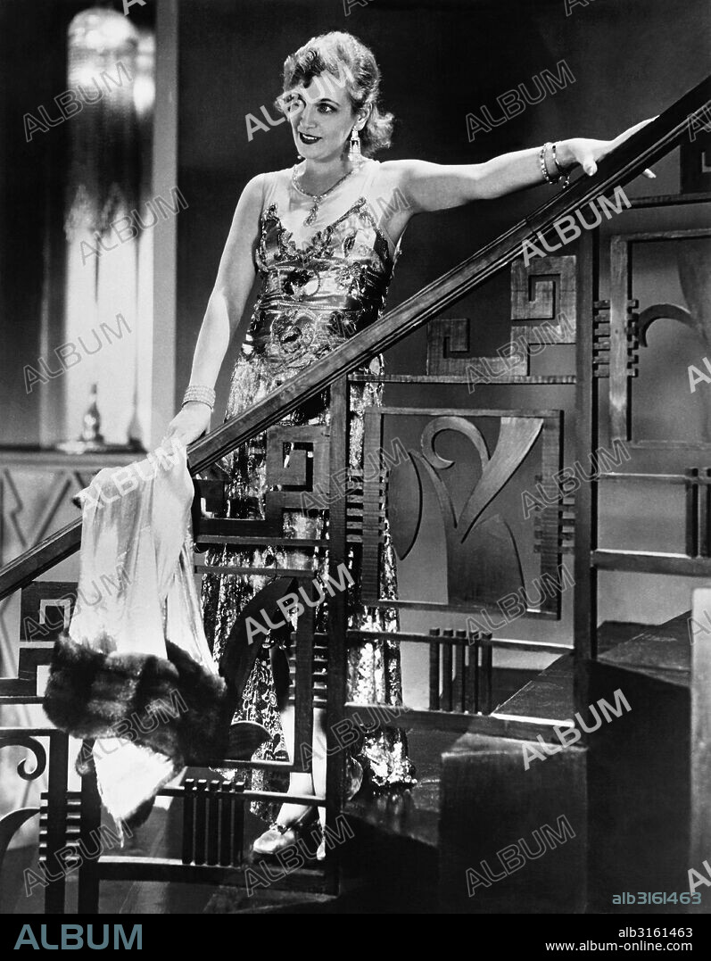 Hollywood, California: c. 1929 Russian movie star Olga Baclanova models an evening gown made of gold cloth, sequins, crystals, and a gold lace. It is worn with a gold coat bordered with sable fur.