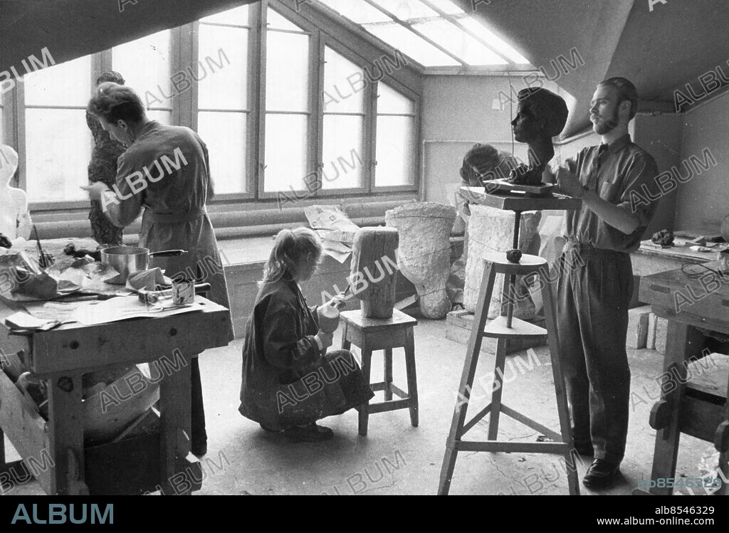 Stockholm 1957-02-09. Undervisning Konstfackskolan.. Lilla Lanterinen är skulptörens käraste tillhåll. Ljuset från takfönstren är perfekt och det går lätt att arbeta i den inspirerande miljön. Olle Jeppsson tv arbetar med en kvinnofigur, Marie-Loise Jönsson trollar fram ett ansikte med klubban och stämjärnet ur ett trästycke och Ulf Suckdorff lägger sista handen vid ett porträtt. Foto: DN / TT / Kod: 192. ** SvD OUT **.