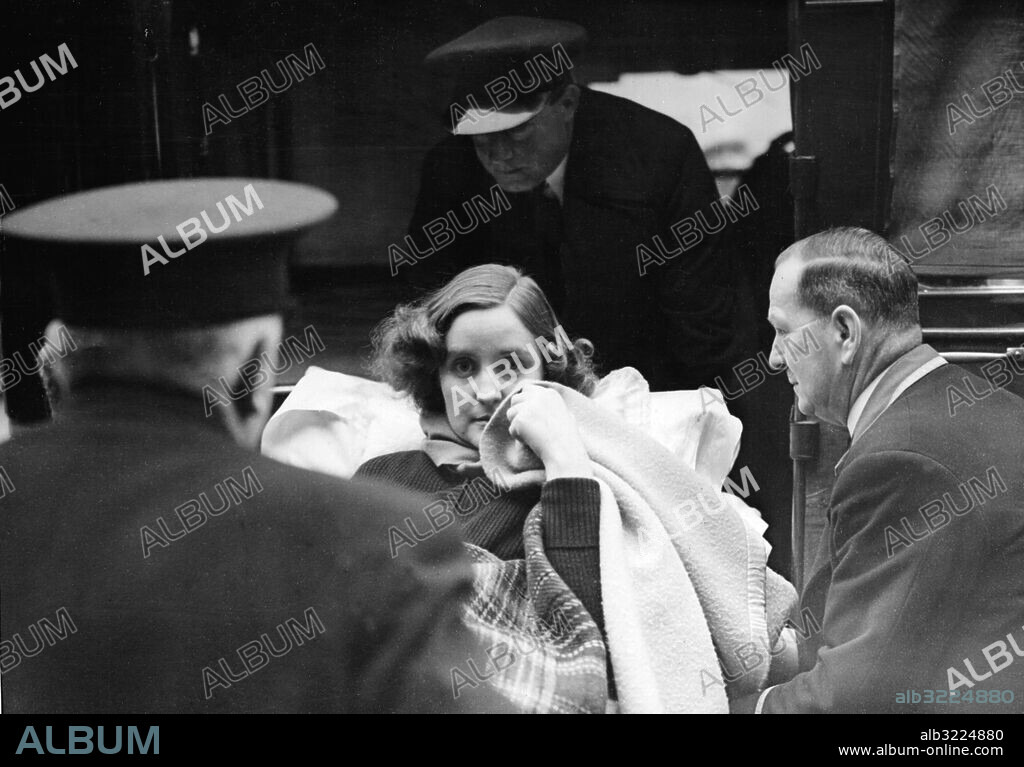 Orig. bildtext... UNITY MITFORD STARTS FOR HOME AFTER TWO DELAYS. After twice being held up - once by an ambulance which broke down and again by an ambulance which arrived late - Miss Unity Mitford, just back in England from Germany, left Folkestone for the home of her father, Lord Redesdale at High Wycombe, Buckinghamshire. She was accompanied by Lord and Lady Redesdale. Miss Mitford, a friend of Hitler, was reported to have been shot in the head, but is now stated to be seriously ill. PHOTO SHOWS:- Miss Unity Mitford being carried from the hotel at Folkestone on a stretcher. January 4th 1940 U Mitford, 1914-1948, brittisk kvinna med uttalade nazistsympatier. På bår Sidbena Döttrar Bårbärare Stirra Sjuklingar Filtar CD657 persons: UNITY MITFORD sites: STORBRITANNIEN;FOLKESTONE.