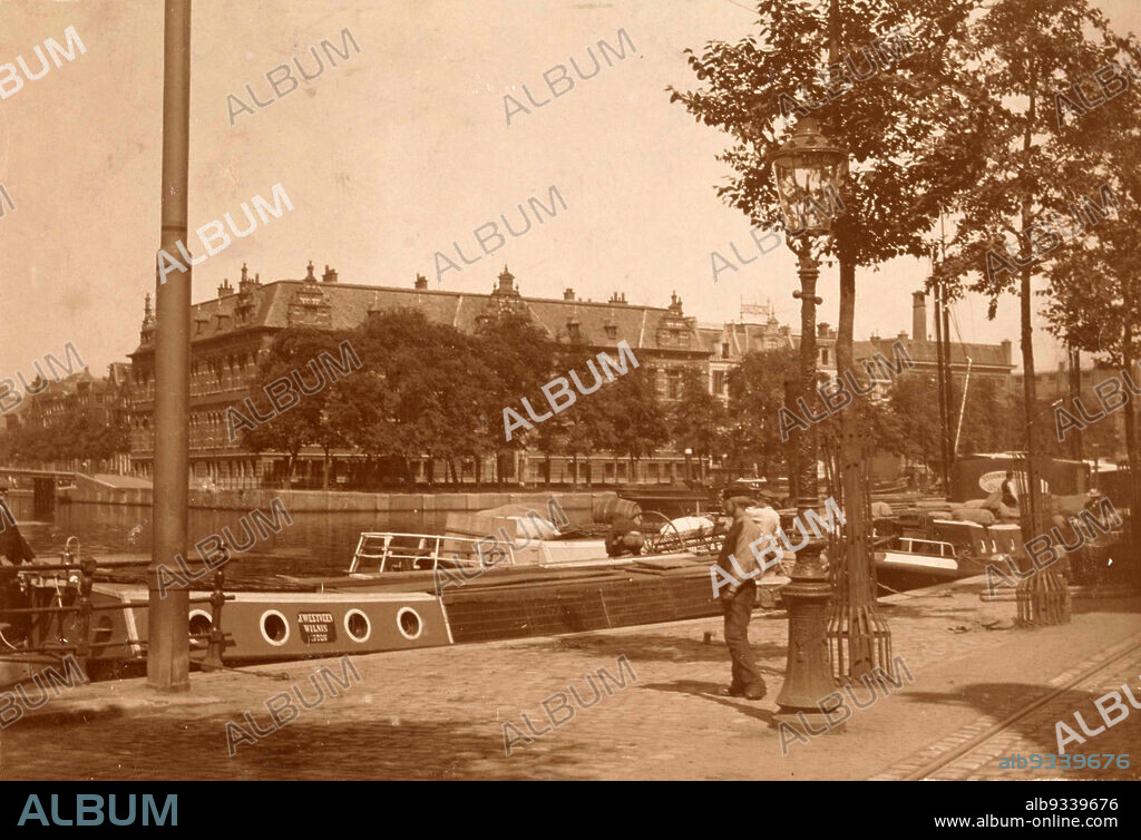 Corner Amstel Zwanenburgwal in Amsterdam, View of the corner of the Amstel the Zwanenburgwal in Amsterdam. On the corner, Amstel 1, the Diaconie orphanage of the Dutch Reformed Community. At number 5 the building of the firm Widow J.T. Hunck, suppliers of coal and gas stoves. Part of a group of 5 photos and 19 stereo photos taken by an unknown amateur photographer around 1900 in Amsterdam, the Ardennes and Denmark., anonymous, Amsterdam, c. 1900, photographic support, cardboard, height 98 mm × width 130 mm.