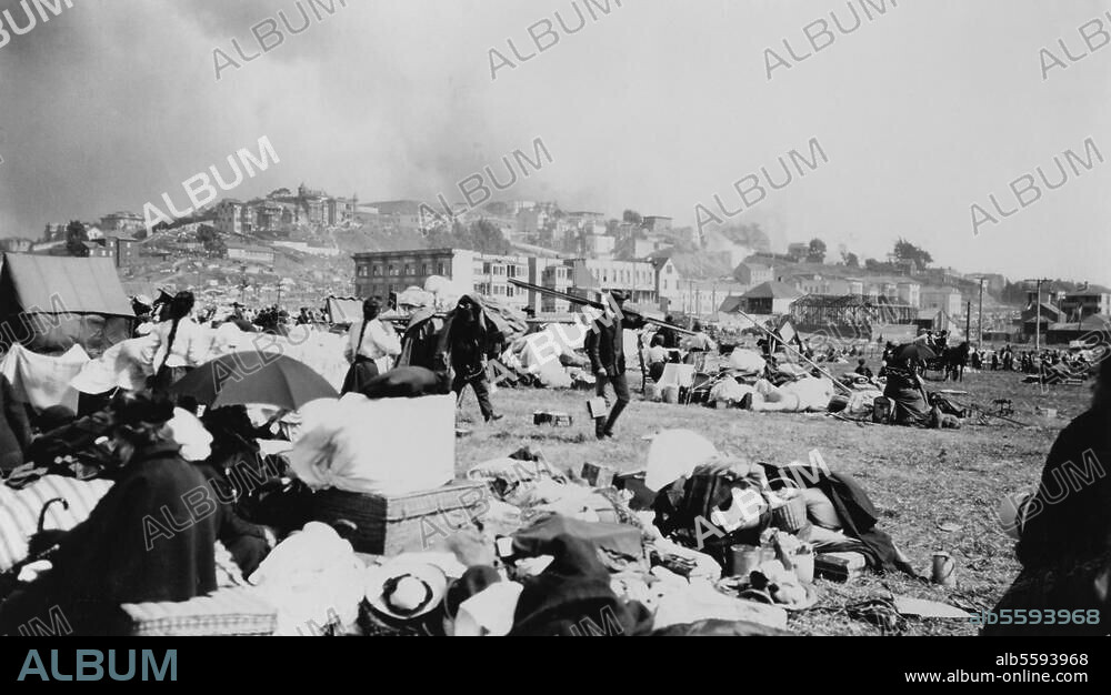 San Francisco (Californie, USA) : tremblement de terre du 18. avril 1906 détruisant la ville et provoquant un immense incendie. Rescapés du tremblement de terre avec leurs affaires ; derrière eux, la ville en ruines.