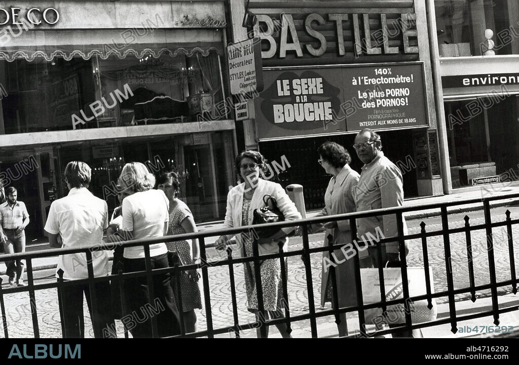 Rue du Faubourg Saint Antoine, passants devant un cinema qui presente des films pornographiques 'Le sexe a la bouche, 140% a l'erectometre, le plus porno des pornos', metro Bastille, cinema Le Bastille, ancien cinema porno. Scene de rue, Vie quotidienne, dans la ville, Paris. Photographie JEAN POTTIER. Credit photo JEAN POTTIER/KHARBINE TAPABOR.