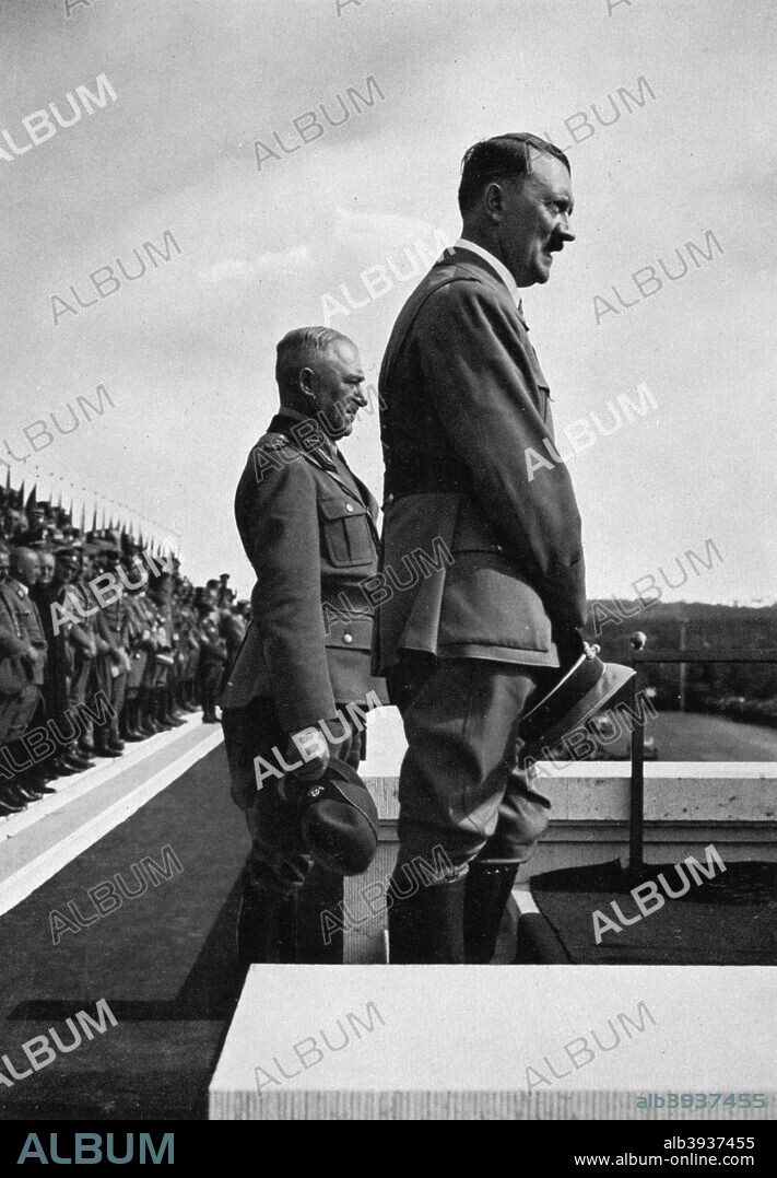 Adolf Hitler with Konstantin Hierl, Nuremberg Rally, Germeny, 1935. Hitler (1889-1945) and Reichsarbeitsdienst (Reich Labour Service) Leader Hierl (1875-1955) before a crowd of 47,000 Labour Service men at the 1935 Party Congress. A print from Adolf Hitler. Bilder aus dem Leben des Führers, Hamburg: Cigaretten/Bilderdienst Hamburg/Bahrenfeld, 1936.