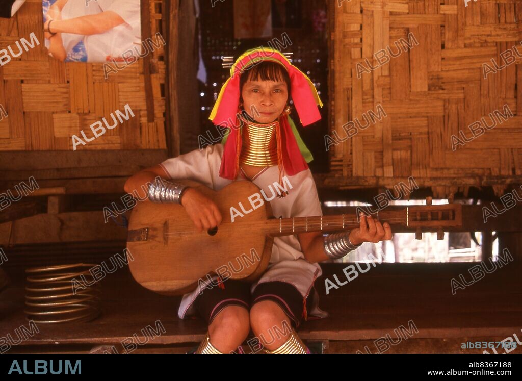 Thailand: Padaung (Long Neck Karen) woman plays a locally produced guitar in a village near Mae Hong Son, northern Thailand. The Padaung or Kayan Lahwi or Long Necked Karen are a subgroup of the Kayan, a mix of Lawi, Kayan and several other tribes. Kayan are a subgroup of the Red Karen (Karenni) people, a Tibeto-Burman ethnic minority of Burma (Myanmar).