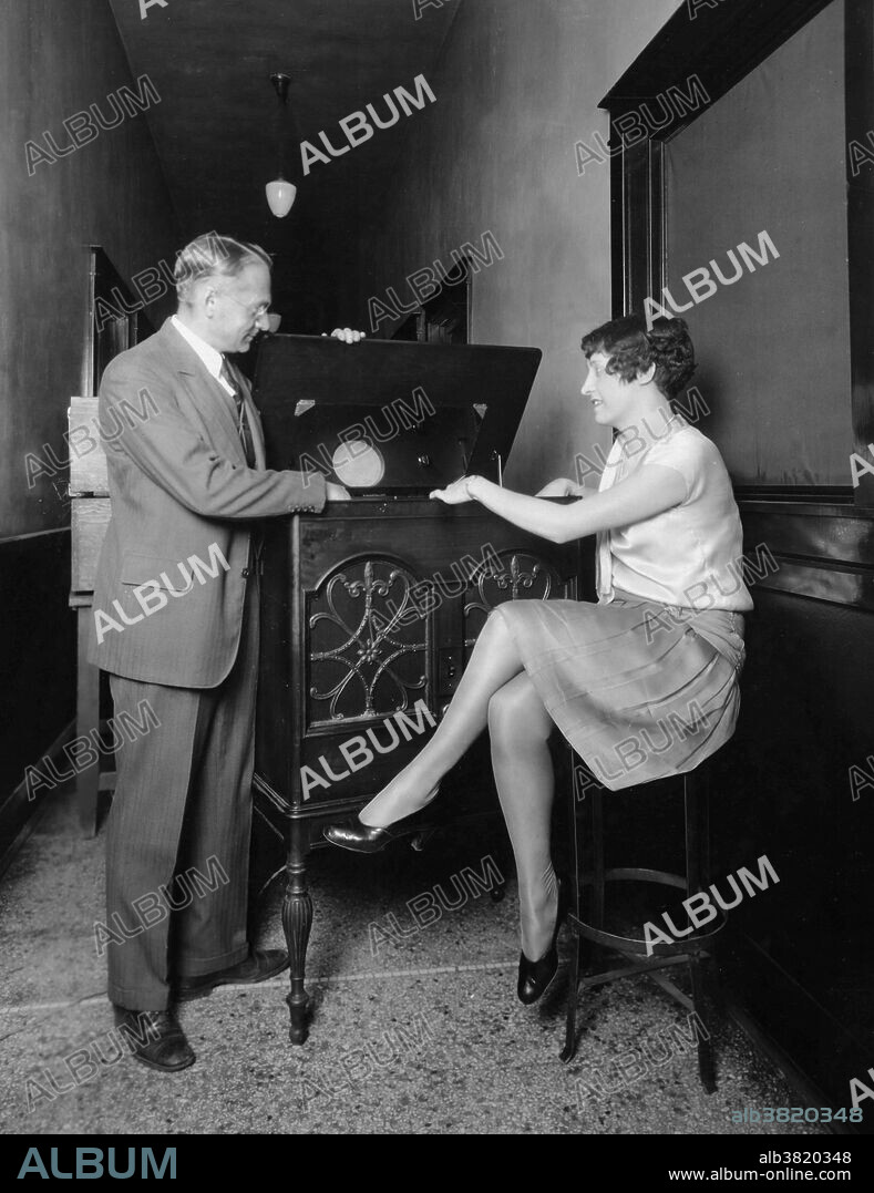 Vladimir Kosma Zworykin (1889-1982), a Westinghouse Electric and Manufacturing Company research engineer, is shown in 1934 demonstrating his new cathode ray television set, "which can entertain large groups instead of one or two spectators." Mildred Birt looks on with interest. The broadcast images are projected on a mirror on the top of the cabinet making it possible for many to watch. The first cathode ray tube to use a hot cathode was developed by John B. Johnson (who gave his name to the term Johnson noise) and Harry Weiner Weinhart of Western Electric, and became a commercial product in 1922. It was named by inventor Vladimir K. Zworykin in 1929. RCA was granted a trademark for the term (for its cathode ray tube) in 1932; it voluntarily released the term to the public domain in 1950. The first commercially made electronic television sets with cathode ray tubes were manufactured by Telefunken in Germany in 1934.