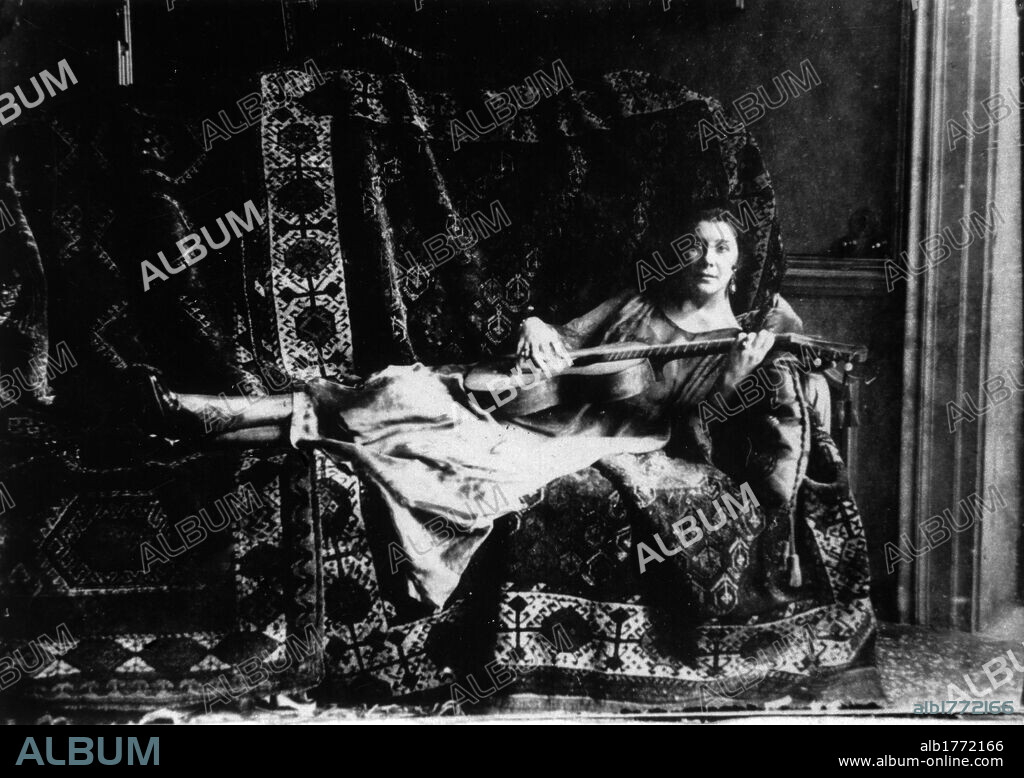 Olga Levi Brunner on a sofa. Italian singer and musician Olga Levi Brunner, Gabriele D'Annunzio's mistress, lying on a sofa with a guitar. First decade of 20th Century.