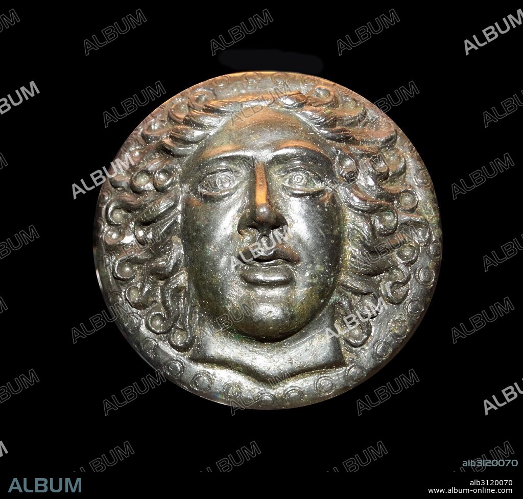 Greek bronze disc, with a head of the sun-god Apollo Helios. 5th-3rd century BC.