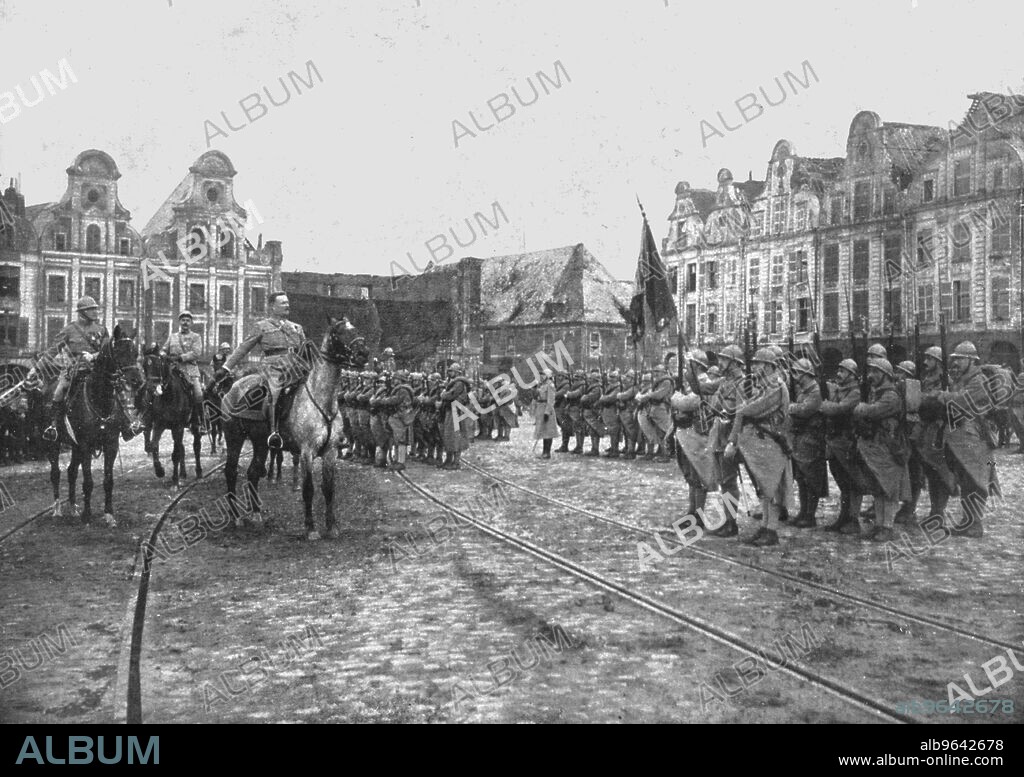 'Le Retour des Vainqueurs; Arras: le salut au drapeau du 33e regiment d'infanterie, le 8 mars 1919, sur la Petite Place, d'ou il etait parti en 1914', 1919. From "L'Album de la Guerre 1914-1919, Volume 2" [L'Illustration, Paris, 1924].