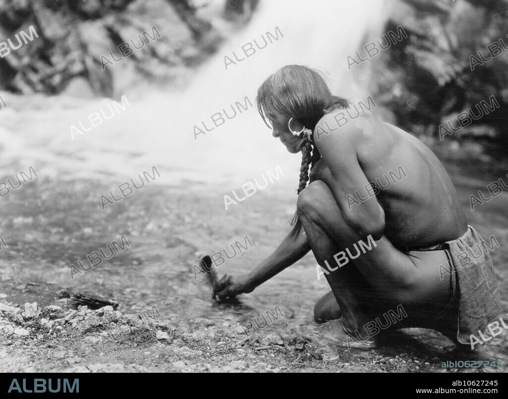 EDWARD SHERIFF CURTIS. An offering at the waterfall-Nambe, 1927 Nambe Indian placing prayer plume at waterfall.