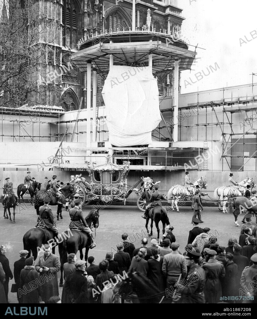 State Coach in Coronation rehearsal . The State Coach , window blind drawn , leaves Westminster Abbey annexe ( still under construction ) during the full - scale rehearsal today of the Coronation procession . 10th May 1953.