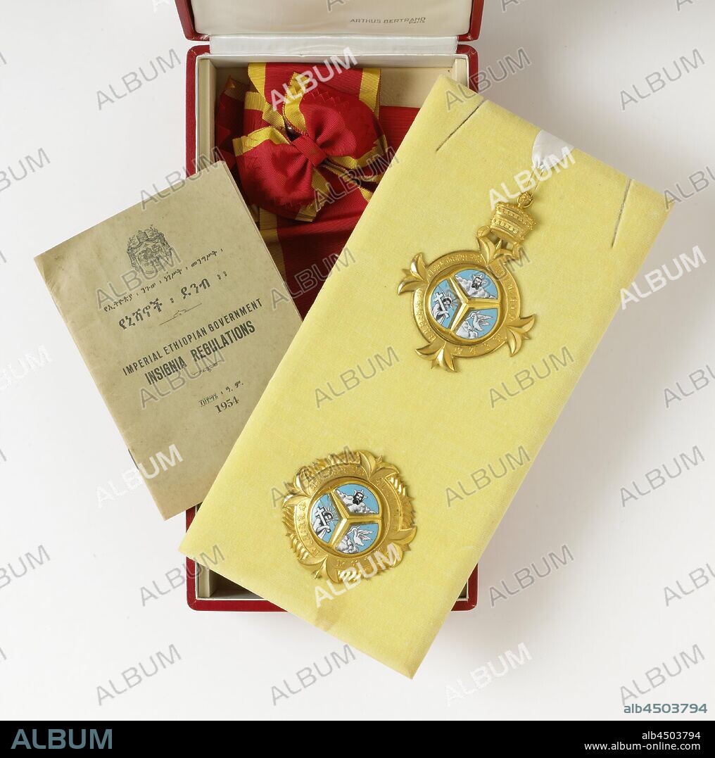 Ethiopian knighthood (Order of the Trinity), received by Willem Drees, Box covered with red paper with the decorations of the Order of the Trinity (1st class), Empire Ethiopia, set in 1930 by Emperor Haile Selassie, granted to Prime Minister W. Drees. The decorations consist of a carrying sign, a shoulder strap and an ordester. The round, golden (gold-plated?) Bear sign is adorned with four protruding floral motifs on the top, bottom and two sides, the top of which is crowned with a crown, and has an inscription written in Ethiopian that reads (freely translated) : 'Blessed are You who see the depths seated on the Cheribon.' In the center, separated by a raised golden star, white enameled images of God, Son and Holy Spirit. The carrier sign is attached to a short white silk cord with a safety pin, which is attached to a yellow velvet base. The ordester is designed in the same way as the bear sign, but without a crown and with flares on the edges as an addition between the flower motifs, a sturdy (gold) pin is attached to the bottom. The loose ribbon is red with yellow side edges and is used as a bow at the attachment for the bear mark. Loosely in the box is a bilingual 34-page brochure with cover, entitled 'Imperial Ethiopian Government / Insignia Regulations' and bearing the date 1954. The Ethiopian text is written in Ethiopian script. The inside of the lid of the box is covered with white silk, bear sign and star lie on a yellow velvet-covered elevation, including the ribbon and brochure, Netherlands, Ethiopia, Willem Drees, Haile Selassi, Arthus Bertrand, Paris, in or after c. 1885, d 7.8 cm w 8.2 cm l 11.4 cm w 7.7 cm l 83 cm × w 20.5 cm l 16.7 cm w 12 cm h 7.2 cm w 16.5 cm × d 32 cm.