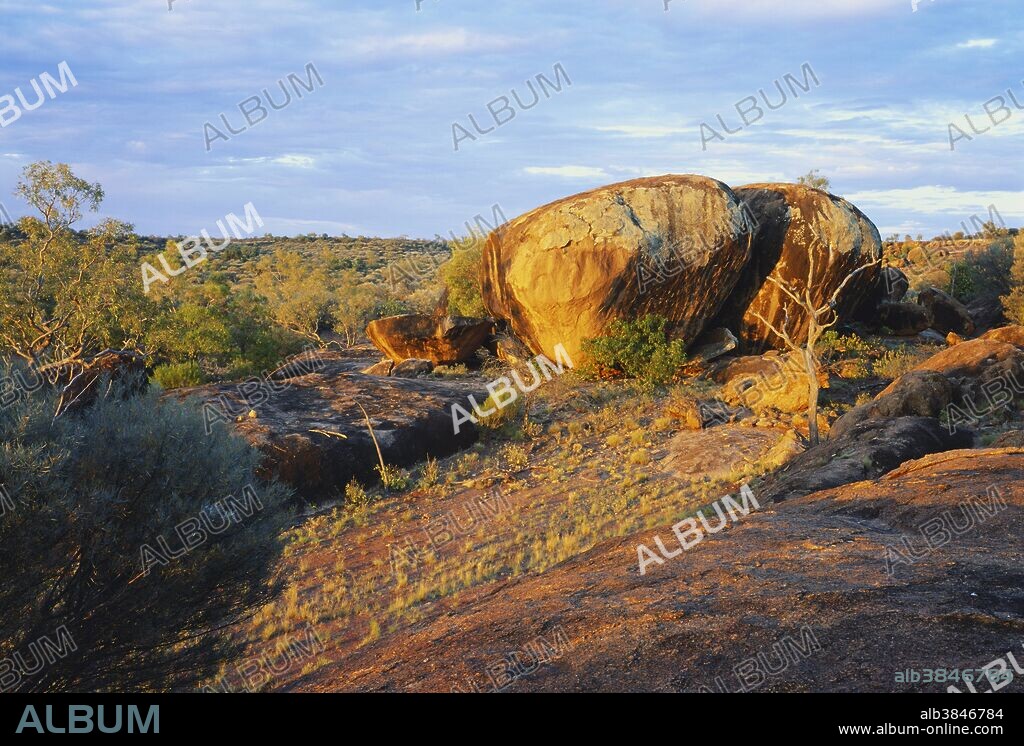 Granite tors, giant rounded boulders created by exfoliation, stand proud of the landscape at The Granites, Currawinya National Park, western Queensland, Australia.  An outcropping of a large underground batholith (an igneous intrusion) in a mostly sedimentary sandstone landscape, the rounded shape of these tors reflects joint lines or cracks in the batholith which created blocks of granite and allowed weathering water to percolate around them, starting the process before surface erosion exposed the rock.