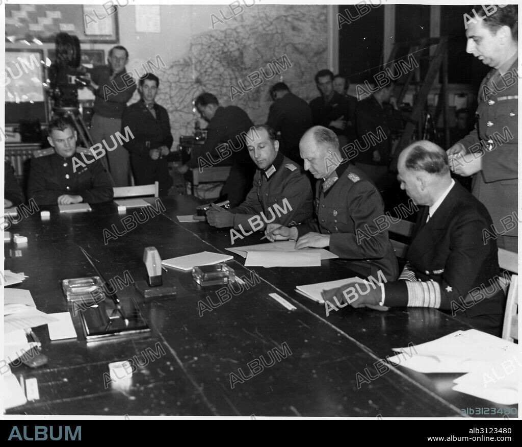 Photograph of Alfred Jodl (1890-1946), German military commander, attaining the position of Chief of the Operations Staff of the Armed Forces High Command during the Dönitz Regime, signing a document of unconditional surrender. Dated 1945.