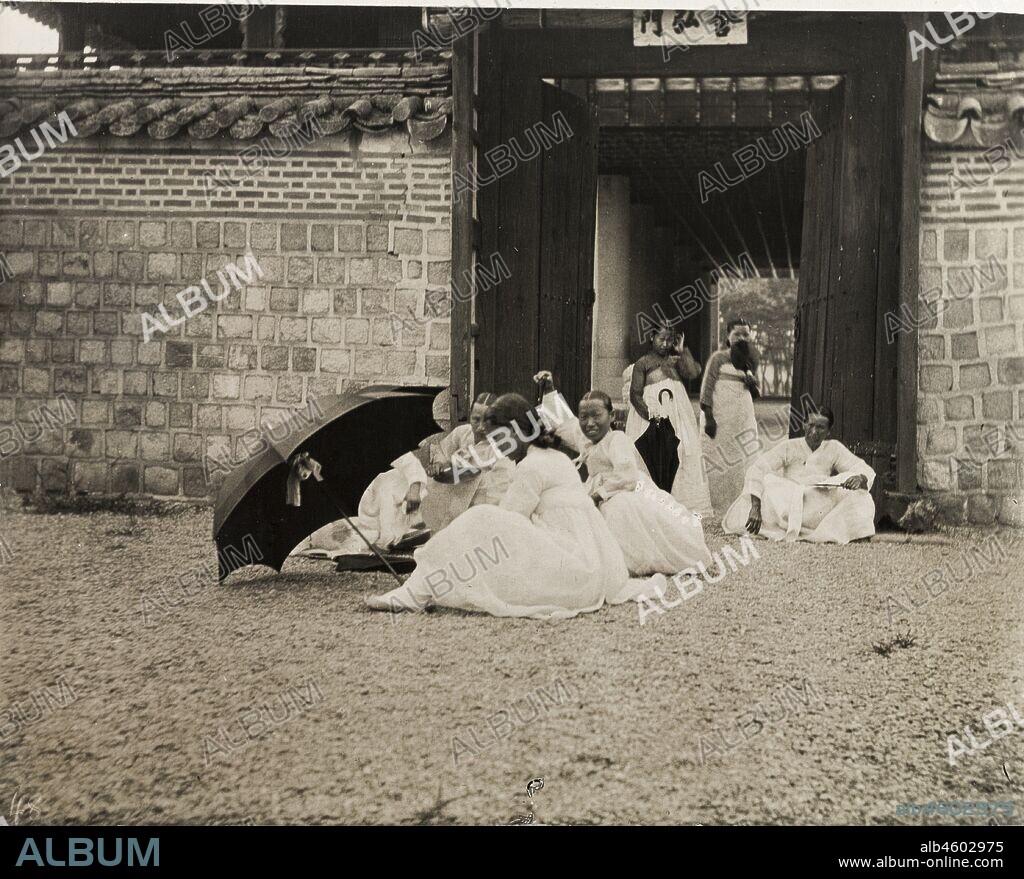 South Korea, A group of Korean women and girls sit in the grounds of an imperial palace in Seoul. All wear traditional 'hanbok' dress, comprising full-length skirts and wide-sleeved, hip-length jackets or shirts. Original manuscript caption: Seoul - Girls and Women in grounds of Imperial Palace, circa 1920. 1998/028/1/1/247.
