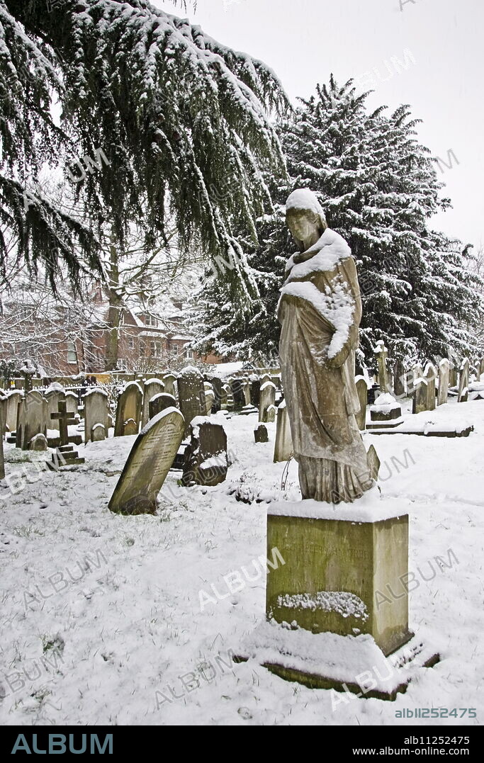 Snow covered monument and gravestones in Hampstead Parish churchyard, London, United Kingdom.
