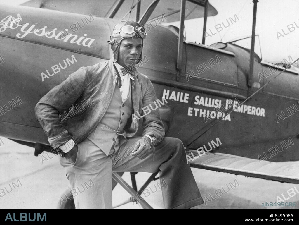 Orig. bildtext... THE BLACK EAGLE OF HARLEM DEPARTS FROM PARIS Colonel Hubert Fauntleroy Julian, the Black Eagle of Harlem and one-time air minister of Ethopia came back to Paris yesterday and found that the French capital had not forgotten him. He left shortly afterwards for England where he hopes to take part in the London-Melbourne air race. The Black Eagle was as debonair and confident as ever. The Photo shows Colonel Julian and his new Engllish plane at Le Bourget. July 16, 1934 Anm. Se även BBX264 Abessinien, Etiopien H Julian, 1897-1983, västindienfödd flygare som fick smeknamnet The Black Eagle när han 1924 gjorde ett misslyckat försök att flyga från New York till Afrika. 1929 lyckades han, två år efter Charles Lindbergh, flyga över Atlanten och ett år senare till Etiopien, där han belönades med medborgarskap och överstes rang. Bildserier Fotoreportage Abyssinia Haile Sallisi 1st Emperor Ethiopia Fluga Flygarmössa Handen i fickan Självförtroende CD597 persons: HUBERT FAUNTLEROY JULIAN sites: ETIOPIEN*;PARIS;FRANKRIKE;USA*.