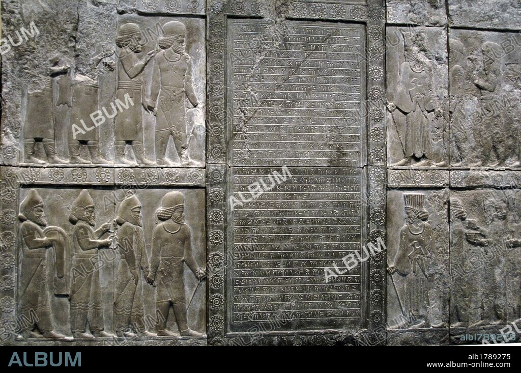 ARTE PERSA. DINASTIA AQUEMENIDA. PERSEPOLIS. S. VI-V a. C. PALACIO DE DARIO I (522-486 a. C.). Detalle de un relieve en el muro exterior de la escalinata de la APADANA o SALON DE RECEPCIONES DEL REY PERSA DARIO I. En la parte central se sitúa una INSCRIPCION CUNEIFORME QUE REGISTRA LA CONSTRUCCION DE UNA ESCALERA EN EL PALACIO DE PERSEPOLIS POR EL REY ARTAJERJES III OCO (425 a. C. -388 a. C.). A ambos lados aparecen tres filas de figuras andando hacia el centro. En la parte izquierda un hombre con INDUMENTARIA MEDA dirige cada grupo; en la parte derecha hace lo propio un hombre con INDUMENTARIA PERSA. Copia del original conservado en su lugar de orígen (Irán), realizada en el s. XIX. Museo Británico. Londres. Inglaterra. Reino Unido.