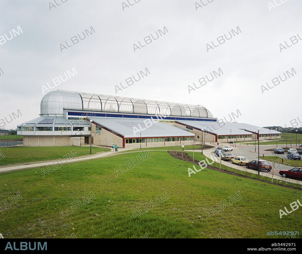 JOHN LAING PLC. Perronet Thompson School, Wawne Road, Bransholme, Kingston upon Hull, 17/04/1989. A view of Perronet Thompson School from the north west. Laing's Yorkshire Region division began work on site in September 1986 and the building was completed in June 1988.  Bransholme was one of the largest local authority housing estates in Britain at the time and the school was equipped with enhanced facilities for the use of the whole community.  These included the larger lending library, the 'Bransholme Theatre', meetings rooms, a gymnasium and courtyard tearooms. The school was named for the Kingston upon Hull born parliamentarian Thomas Perronet Thompson (1783-1869), a governor of Sierra Leone and activist against the Corn Laws. It closed in 1999 and reopened as Kingswood College of Arts but was demolished in 2011 and replaced on the same site by a new building, the Kingswood Academy. This view shows three of the six year-block modules built in pairs along the 18m high barrel vaulted spine. The clear polycarbonate barrel vault was four times longer than any other in the UK and spanned 11m.