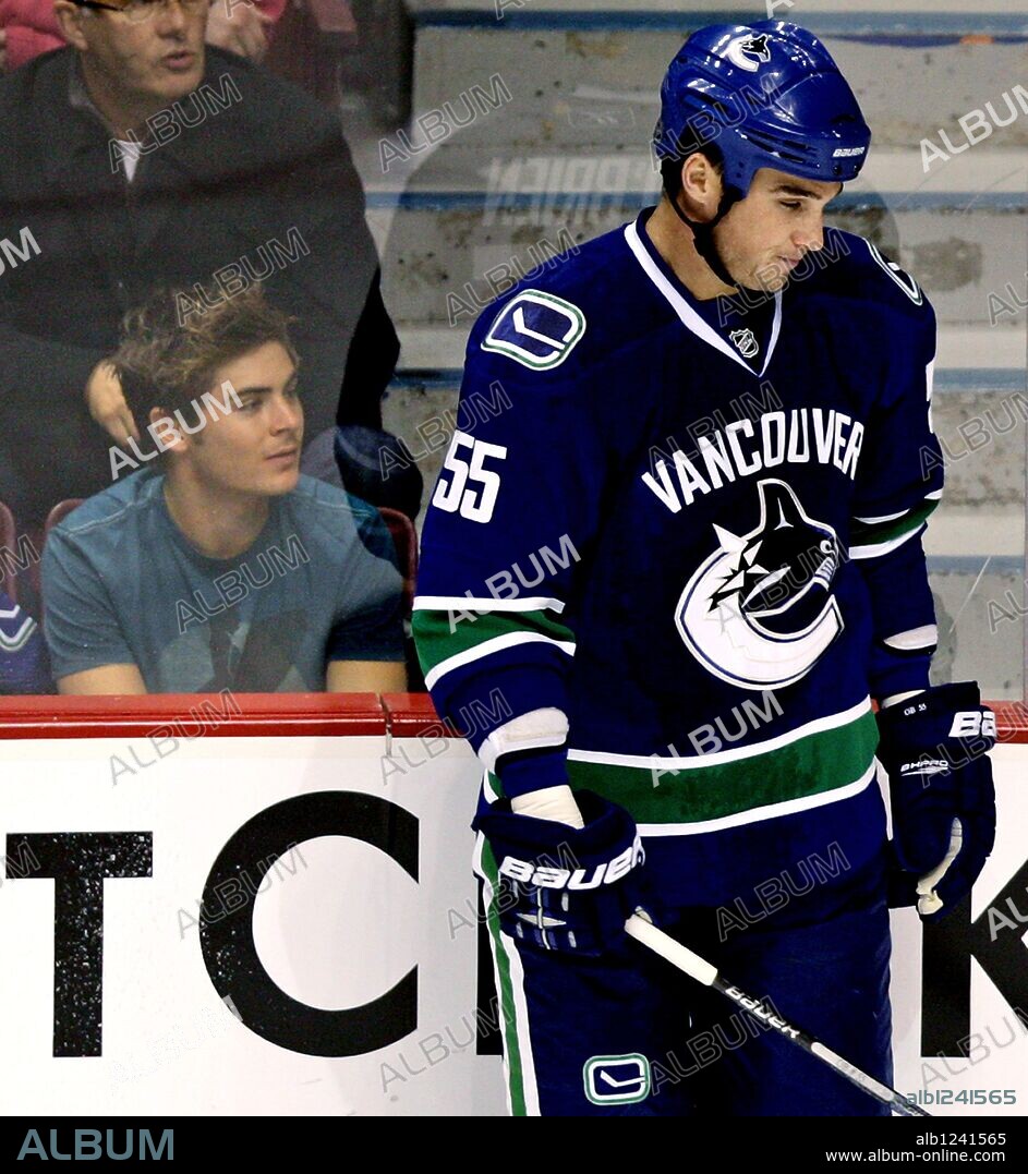 Actor Zac Efron, left, attends an NHL hockey game featuring the Vancouver Canucks and Dallas Stars as Vancouver Canucks Shane OBrien, right, stands on the ice in Vancouv