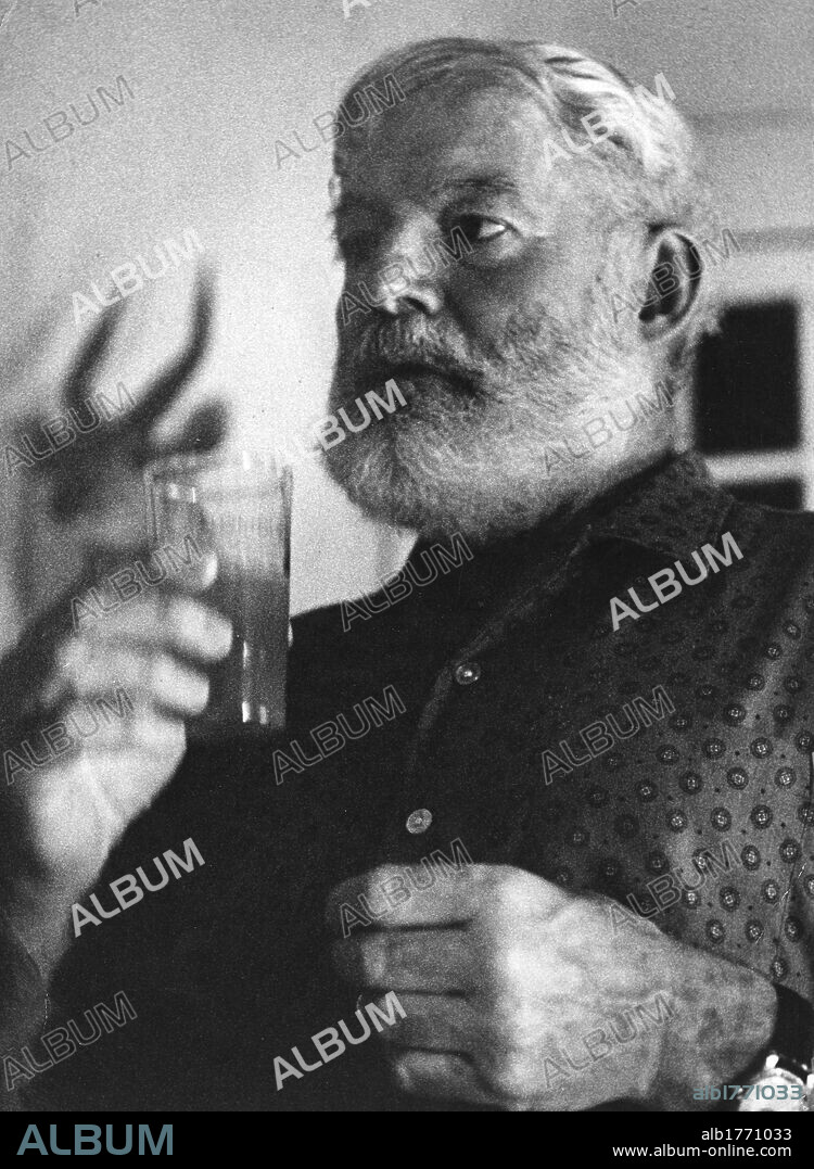 Ernest Hemingway with a glass in his hand. The American writer Ernest Hemingway posing in his Cuban house holding a glass. San Francisco de Paula, 1950s.