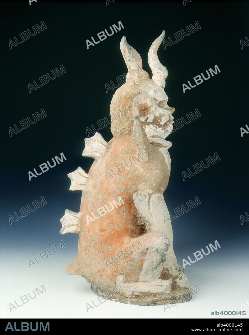Pottery zhenmushou (a tomb guardian beast), early Tang dynasty, China, 7th century. A large pottery zhenmushou with dog-like body seated on all fours on a flat plinth. The creature has horns on its forehead and shoulders, a flame point on its head and three fins on its back. The human face has a pair of large ears at right angles, the feet has hooves like a horse. The piece shows traces of unfired pigment and slip.