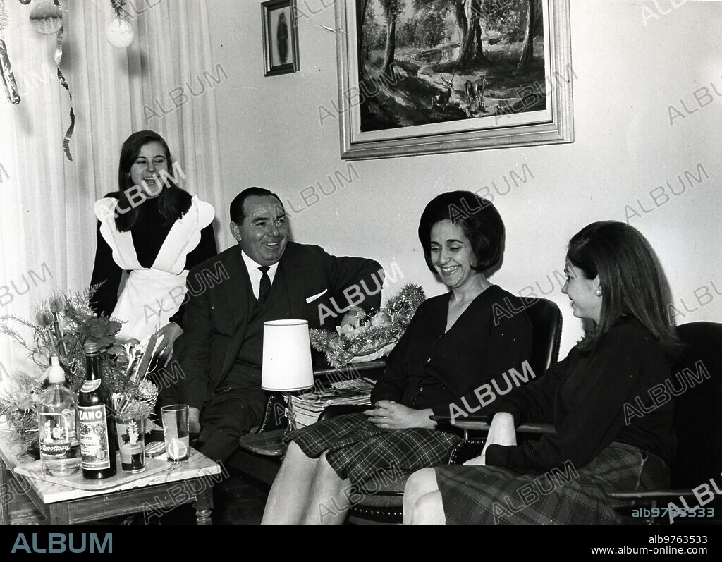 21 diciembre 1965. Don Francisco Gómez Manzanares -aquí fotografiado con su esposa y su hija Mari Carmen- cobrará quince millones de pesetas, de los cuales tres millones setecientas cincuenta mil pesetas corresponden a su hermano político don Andrés Garrido y setecientas cincuenta mil a cada una de sus tres hermanas. La sonriente sirvienta que aparece al fondo no juega ni un céntimo en el número agraciado.