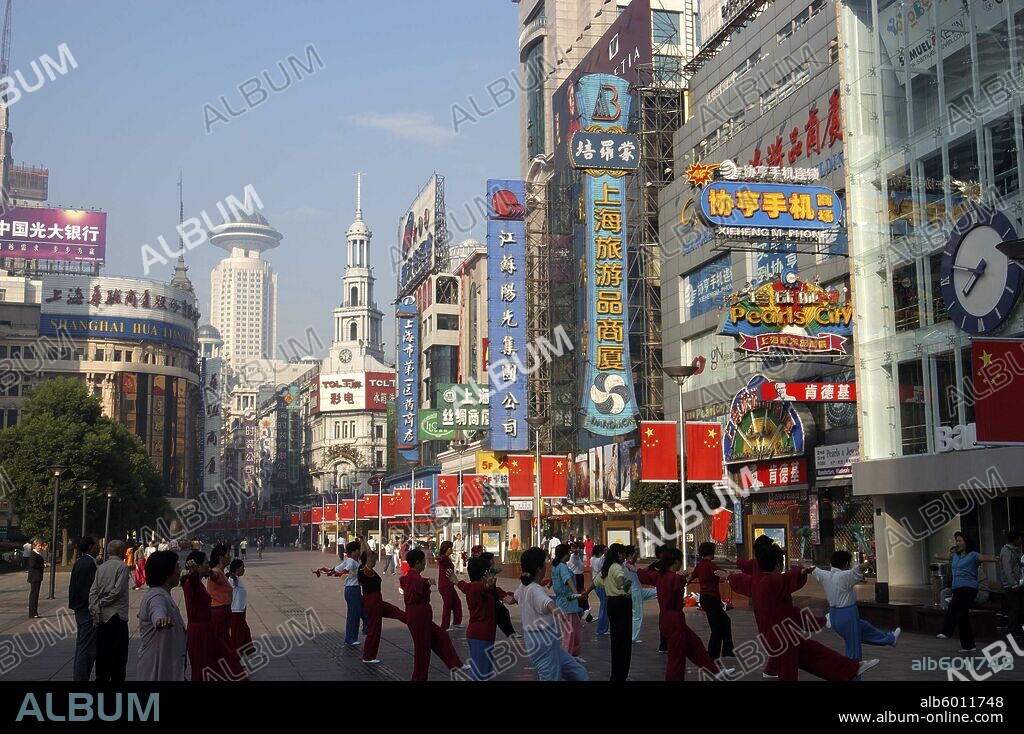 CHINA Shanghai Nanjing Road walking street. Commercial shopping street with group of people exercising outside.