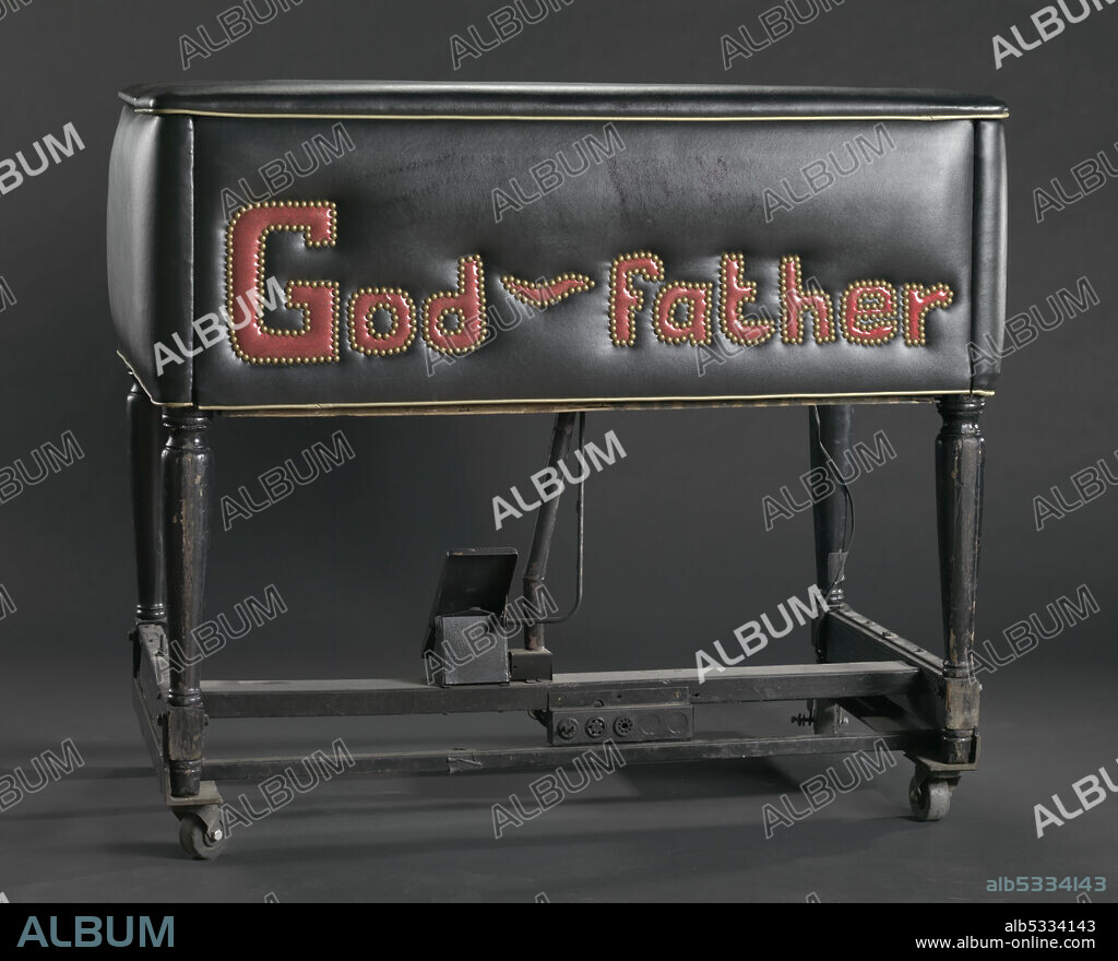 A Hammond B-3 electric organ. The organ is covered in black vinyl and trimmed with silver roping. Stitched on the back of the organ in red vinyl and brass colored metal rivets is "God ~ father." The organ has two keyboards with both preset and manual keys, a folding top and a single foot pedal. Electrical outlets are on the back of the organ at its base. 'Godfather of Soul' James Brown (1933-2006) was an African-American singer, songwriter, dancer, musician, record producer, and bandleader, and an unparalleled influence on the development of funk music.