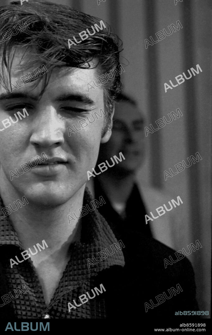 Vintage candid image of The King, Elvis Presley photographed early in his career in 1956 in Memphis Tennessee by Lloyd Dinkins.. Elvis Aaron Presley, also known simply as Elvis, was an American singer, musician, and actor. He is regarded as one of the most significant cultural icons of the 20th century and is often referred to as the "King of Rock and Roll" or simply "The King". His energized interpretations of songs and sexually provocative performance style, combined with a singularly potent mix of influences across color lines during a transformative era in race relations, led him to great success and initial controversy.