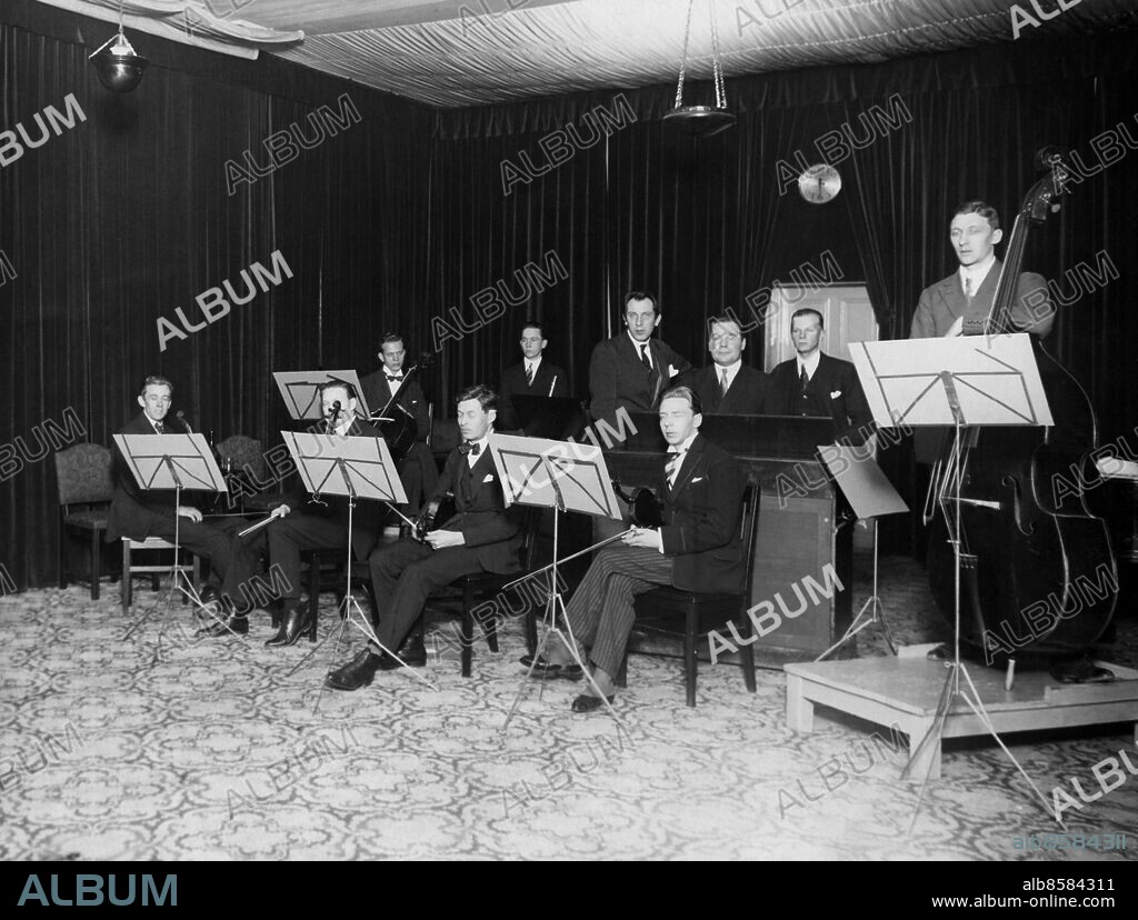 STOCKHOLM 1925.. Utan bildtext. Not. RADIOORKESTERN 1925 i studion Malmskillnadsgatan 30. Från vänster till höger: Gösta Anell, Ernst Törnqvist, Allan Wiggberg, Gustaf Ohlsson, Otto Strinnholm (tillfällig), Hilding Rosenberg (dir.), William Daumne, Ludwig Warschewskij, Gösta Hådell, Ernst Malmqvist. Sommaren 1925 blev Charles Barkel dirigent. Anm. L5 Lokaler Malmskillnadsgatan persons: GÖSTA ANELL;ERNST TÖRNQVIST;ALLAN WIGGBERG;GUSTAF OHLSSON;OTTO STRINNHOLM;HILDING ROSENBERG;WILLIAM DAUMNE;LUDWIG WARSCHEWSKIJ;GÖSTA HÅDELL;ERNST MALMQVIST sites: SVERIGE;STOCKHOLM.