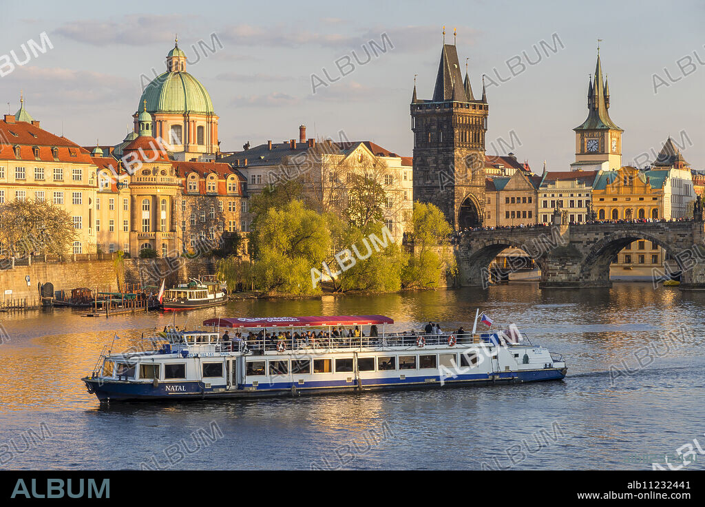 Tourist boat passing Charles Bridge and the Old Town Bridge Tower on Vltava River, Prague, Bohemia, Czech Republic, Europe.