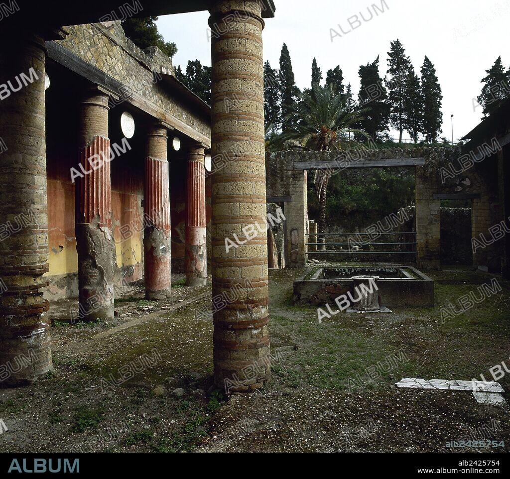 Casa del relieve de Télefo, con la casa adyacente de la Gema. (Comer. Ins, I, 2). Construido en tres niveles. Período de Augusto (27 aC-14 dC) y fue remodelado después del terremoto en 62 dC. Vista del atrio a nivel de calle. Es similar a un peristilo, con columnas que sostienen no las pendientes del techo, sino las habitaciones del piso superior. Entre las columnas cuelgan los moldes de yeso del mármol oscila (discos tema dionisíaco). Campania.