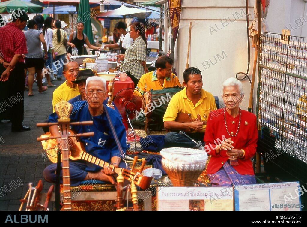 Thailand: A group of traditional Thai musicians known as a <i>wong khrueang sai</i> (string ensemble) entertain the general public at Chiang Mai's famous Sunday Walking Street Market.<br/><br/>. A typical <i>khrueang sai</i> ensemble features two two-string fiddles, one high and one low (<i>saw duang</i> and <i>saw u</i>), a three-string zither called <i>jakhe</i>, a vertical duct flute called <i>khlui</i>, hand drums, and various <i>ching</i> or cymbals. Depending on the size of the ensemble, instruments may be doubled or left out.