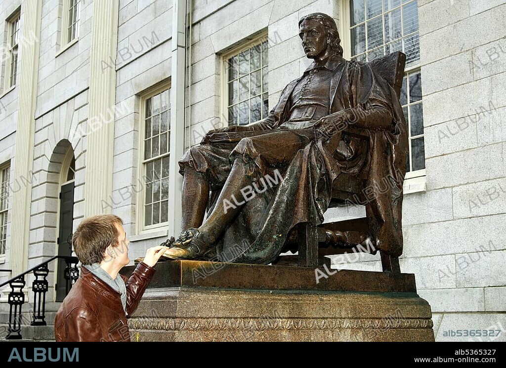 Student at the John Harvard statue by Daniel Chester French, the touch of the shoe will bring luck in exams, Harvard University, Cambridge, Massachusetts, USA