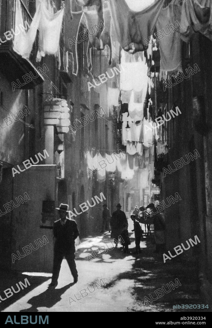 MARTIN HUERLIMANN. Narrow street in Naples, Italy, 1937. Back street with washing on lines. Illustration from Das Mittelmeer: Landschaft, Baukunst und Volksleben im Kreise des Mittelländischen Meeres, a work on Mediterranean architecture, landscape and people by Martin Hürlimann, (Atlantis-Verlag, Zurich, 1937).