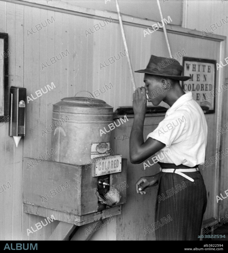 Entitled: "Negro drinking at "Colored" water cooler in streetcar terminal, Oklahoma City, Oklahoma." Segregation is separation of humans into racial groups in daily life. It may apply to activities such as eating in a restaurant, drinking from a water fountain, using a public toilet, attending school, going to the movies, riding on a bus, or in the rental or purchase of a home. Racism consists of both prejudice and discrimination based in social perceptions of biological differences between peoples. It often takes the form of social actions, practices or beliefs, or political systems that consider different races to be ranked as inherently superior or inferior to each other, based on presumed shared inheritable traits, abilities, or qualities. After the Thirteenth Amendment abolished slavery in America, racial discrimination became regulated by the so-called Jim Crow laws, which mandated strict segregation of the races. This legislation that mandated segregation lasted to the mid-1960s. Institutionalized racial segregation was ended as an official practice by the efforts of such civil rights activists as Clarence M. Mitchell, Jr., Rosa Parks, and Martin Luther King Jr., working during the period from the end of World War II through the passage of the Voting Rights Act and the Civil Rights Act of 1964 supported by President Lyndon B. Johnson. Photographed by Russell Lee, July 1939.