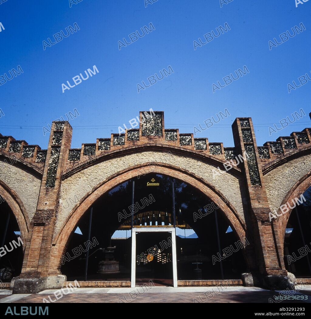 JOSEP PUIG I CADAFALCH. Cavas Codorniu, 1902-1915. Entrada al Porche de las Prensas, actual Museo. Fachada con arcos apuntados y frontón escalonado. Uso del ladrillo, la piedra y el trencadís de cristal verde. Sant Sadurní d'Anoia.