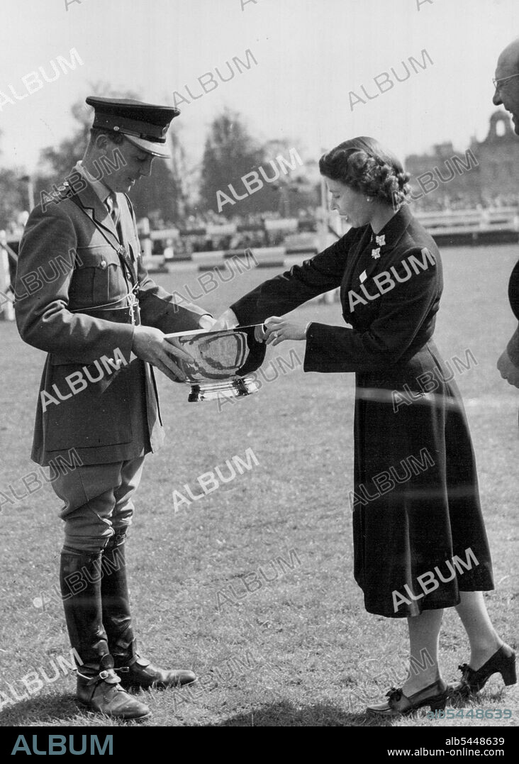The Queen Presents The Trophy To Guard Winner At Badminton -- HM the Queen photographed yesterday, Friday, presenting the trophy to Captain H.A.Q. Darley, of the Royal Horse Guards, winner of the three-day equestrian test at Badminton. The Queen, the Duke of Edinburgh and Princess Margaret, at present staying at Badminton House, Glos., as guests of the Duke of Beaufort, have been spectators at the British Horse Society's Olympic Trials held i the grounds of their host's estate for the past three days. April 26, 1952. (Photo by Fox Photos).