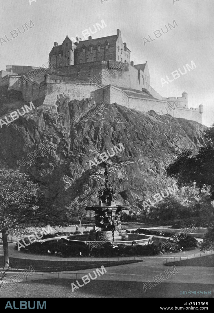 The Castle and Ross Fountain, Edinburgh, 1924-1926. The ancient stronghold of Castle Rock, an outcrop of volcanic rock, has been fortified since 900 AD. The ornate iron fountain was cast in France and displayed at the Great Exhibition of 1862 in London. Daniel Ross, a Scottish gun manufacturer and philanthropist, purchased it and had it transported, in 122 pieces, to Edinburgh, where it was reassembled in Princes Street Gardens in 1872. A print from Hutchinson's Britain Beautiful, edited by Walter Hutchinson, volume II, 1924-1926.