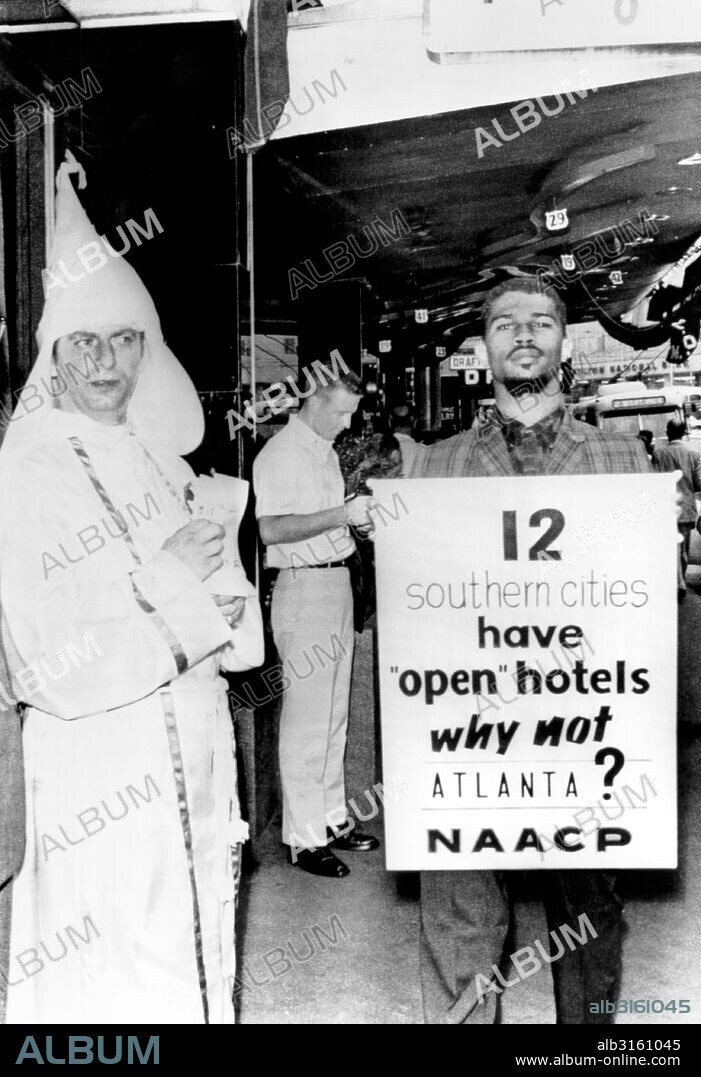 Atlanta, Georgia: July 3, 1962 A delegate to the NAACP convention pickets in front of a downtown hotel protesting its segregation policy while a member of the Ku Klux Klan hands out literature supporting their position.