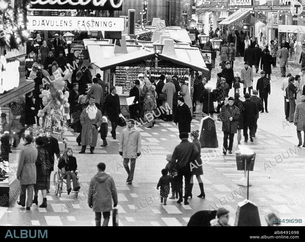 Stockholm 1970-11-29. Skyltsöndag. Sergels torg är fyllt med folk. Snön har kommit och det blir nära till jul. Här tittas i fönster man handlar i bodar och äter varmkorv.. Foto: Expressen / TT / Kod: 192. ** AFTONBLADET OUT **.