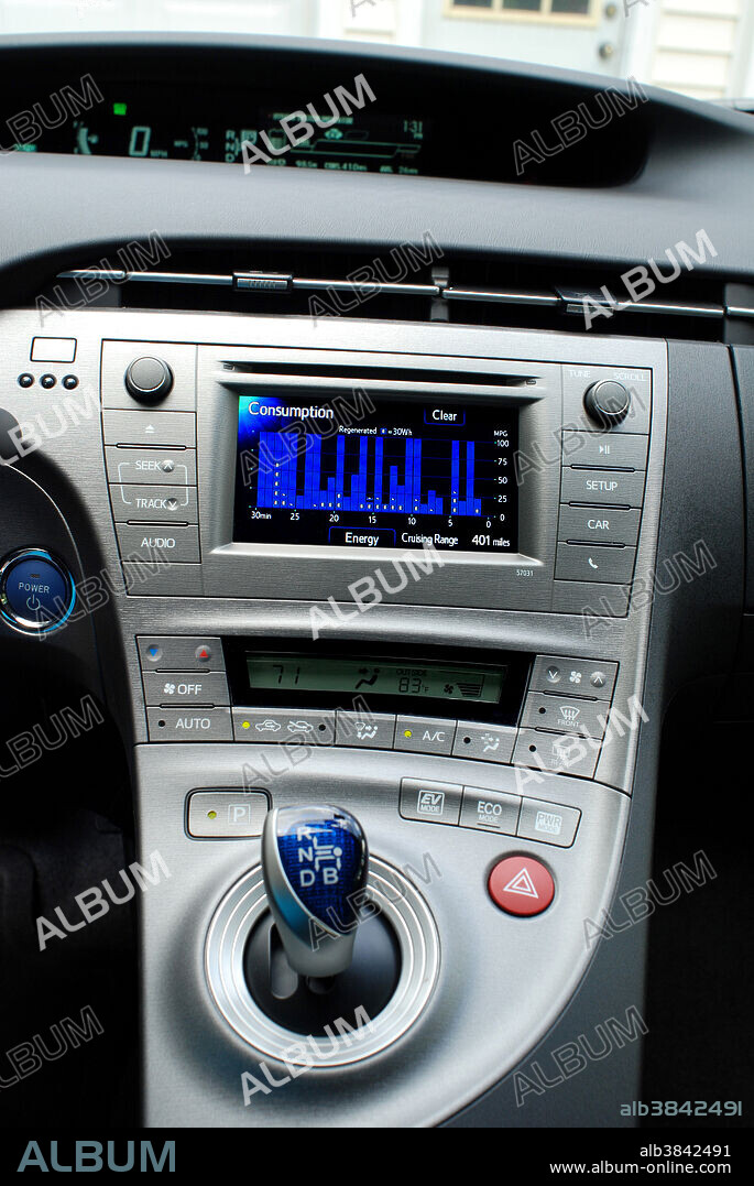 Central console of a Generation III Toyota Prius Hybrid, showing the consumption monitor. Hybrid cars utilize a battery to store energy generated by braking and coasting and use it to drive an electric motor in tandem with a small gasoline engine. Together they provide power to drive the car, while using less gasoline than an internal combustion engine alone.