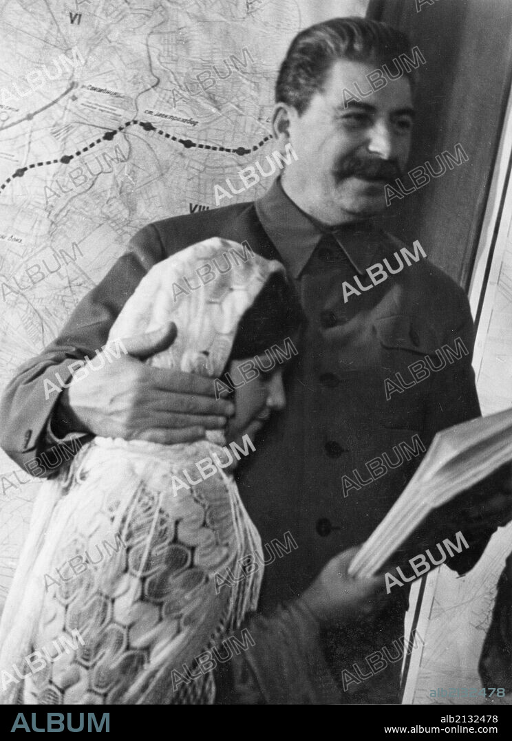 Propaganda photo of josef stalin as benevolent father figure with eleven year old mamlakat nakhangova, a schoolgirl from the lakhuti collective farm, stalinabad region, tajikistan soviet republic, kremlin palace, moscow, ussr, december 1935.