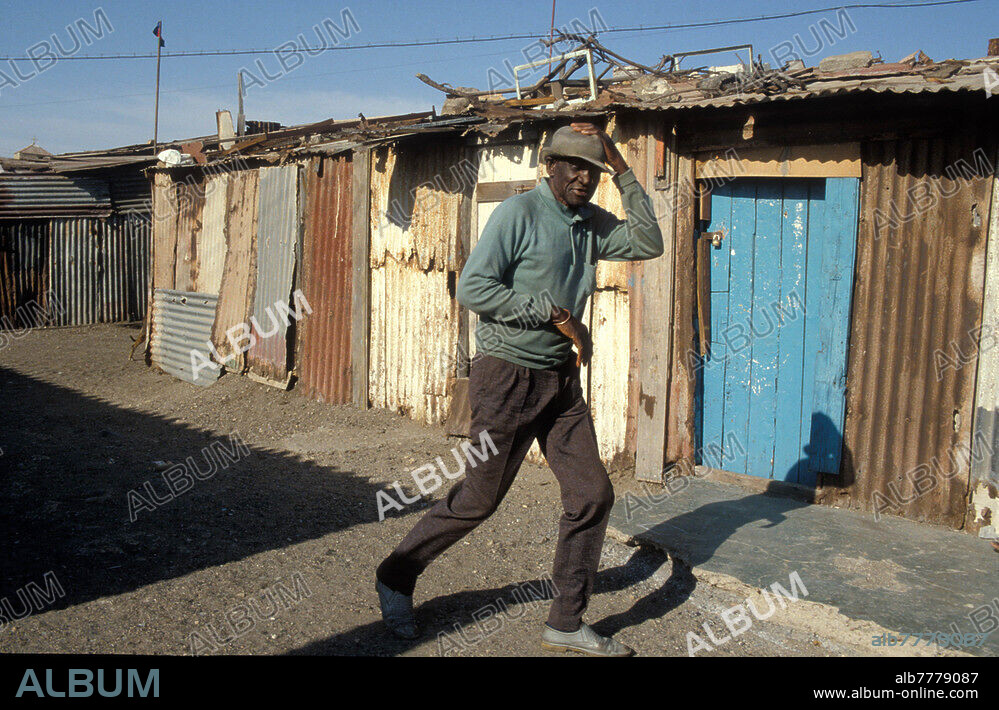 Namibia, Namibias Weg zur Unabhaengigkeit (1884-1920 Kolonie Deutsch-Südwestafrika, 1920 bis 1990 als Mandatsgebiet des Völkerbund Teil von Südafrika), Mondesa - ein Township für die Schwarzen in Swakopmund, Wohnbaracken der schwarzen Bevölkerung, in denen der Großteil der Einwohner von Swakopmund lebt, Strassenszene, alter Mann vor Wellblechhütten. Swakopmund, 1988.
