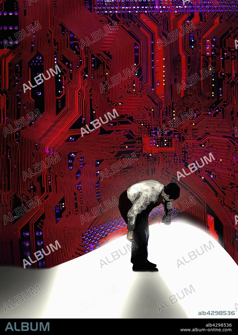 Man lifting up and looking under circuit board.