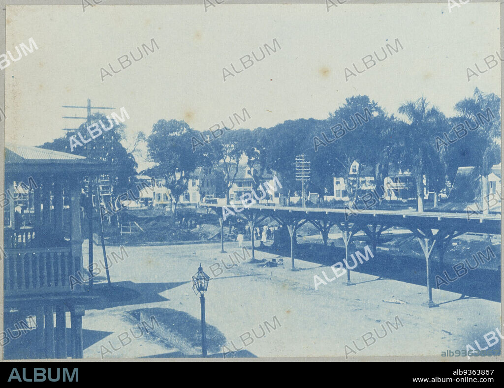 Heiligenweg and Vaillantsplein, Paramaribo (title on object), View of Heiligenweg with covered passage and Vaillantsplein in Paramaribo. Part of the photo album Souvenir de Voyage (part 1), about the life of the Doijer family in and around the plantation Ma Retraite in Suriname in the years 1906-1913., Hendrik Doijer (attributed to), Suriname, 1906 - 1913, photographic support, cyanotype, height 80 mm × width 112 mm.
