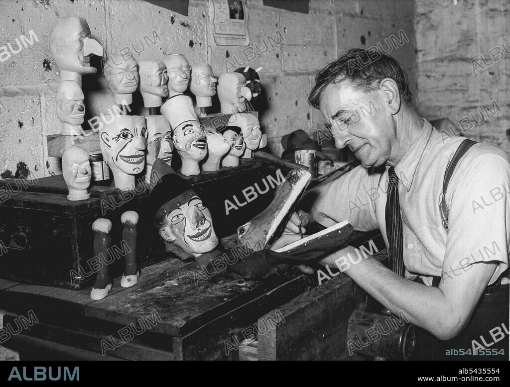 Maker Of Punch And Judy And "Family" -- Mr. Wal Kent putting the finishing touches to a Crooadile's head, one of the characters in the show. Mr. Wal Kent, a veteran Kent entertainer, who lives at Brunawick Road, Gravesend, believes in putting punch into his production drive. He is one of the few men in the country today, who, makes his living mainly by making sets of dolls for the famous Punch and Judy showmen, Mr. Kent is 68 years of age, and has spent a quarter of a century on the boards most.