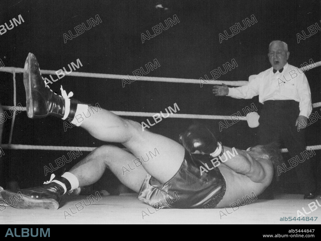 Randolph Turpin retained his British Empire light-heavyweight championship and won the British title, by knocking out Alex Buxton after two minutes and fourteen seconds of the second round at Harringay last night (26-4-55). A typical Turpin thunderbolt rally in which he sank his left fist deep into Buxton's short ribs followed by a finisher to the jaw ended the fight. Buxton heaved and tugged at himself to get up on the points of his feet during the count to continue the fight but while he was still hauling himself erect (see picture) referee Ben Green shouted "Ten" - and the fight was over. April 27, 1955.