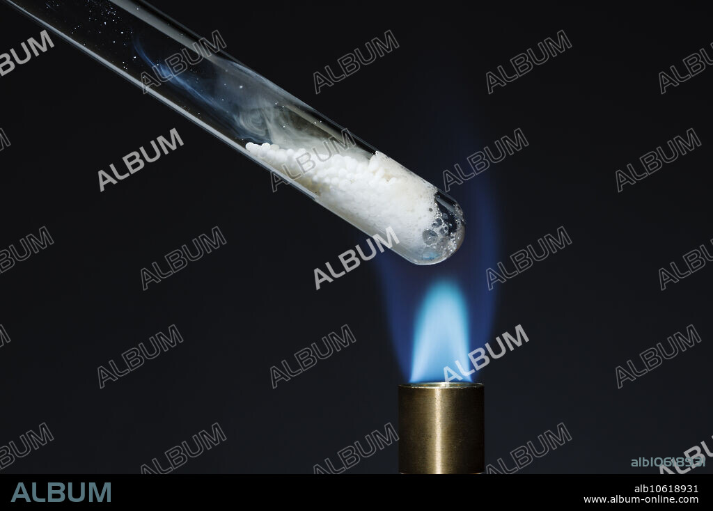 Decomposition of ammonium nitrate, 2 of 3. A test tube with ammonium nitrate, NH4NO3, is placed over a Bunsen burner flame. When heated, ammonium nitrate decomposes into nitrous oxide gas, N2O, and water, H2O: NH4NO3 -> N2O + H2O.