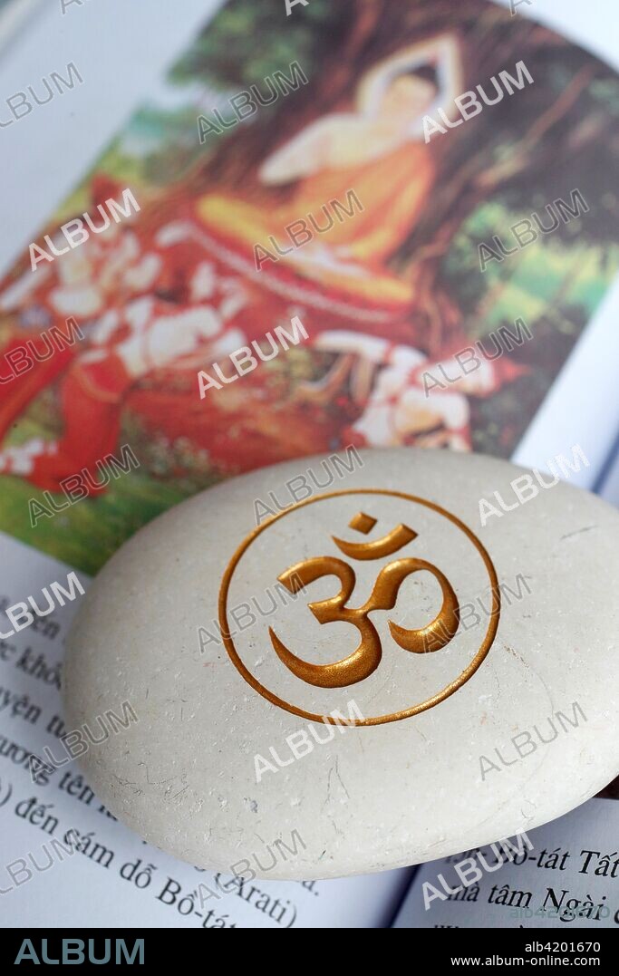 The Om or Aum symbol of Hinduism and Buddhism on a white stone. Book of the life of Buddha.